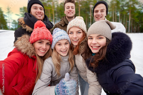 winter, friendship and people concept - group of friends taking selfie outdoors over natural background