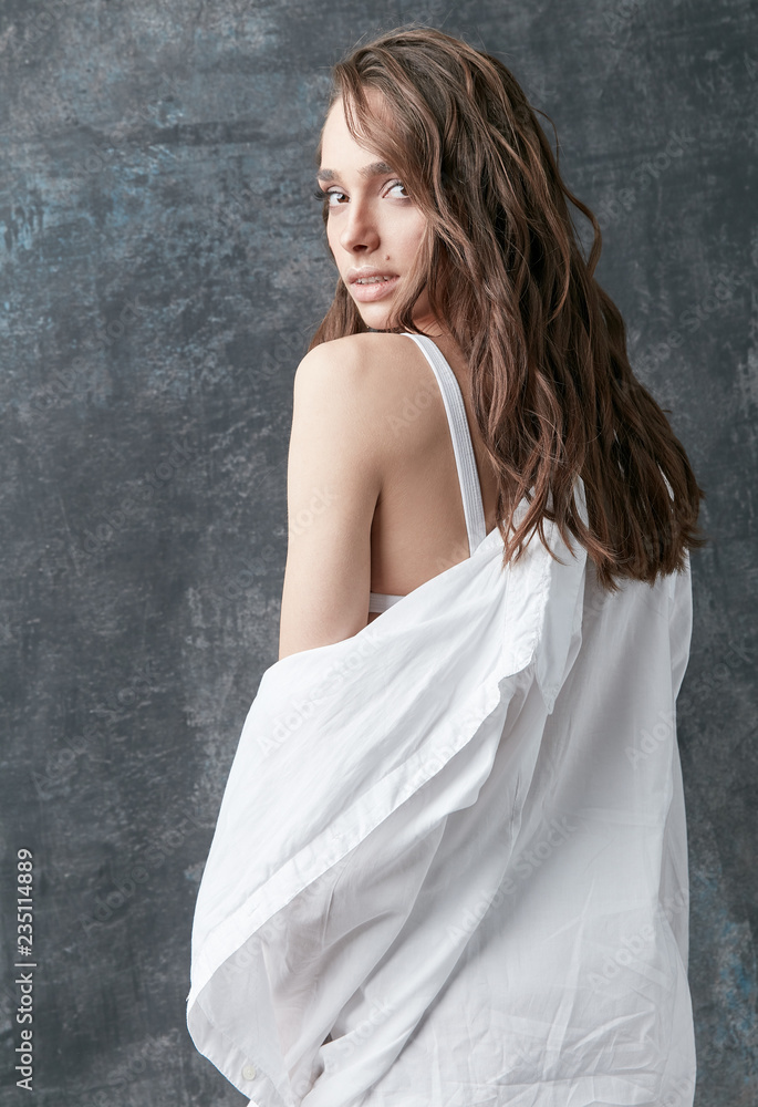 Fashion shot of beautiful brunette woman posing in white shirt, top and pants. Studio, grey background Fashion shot of beautiful brunette woman posing in white shirt, top and pants. Studio, grey background