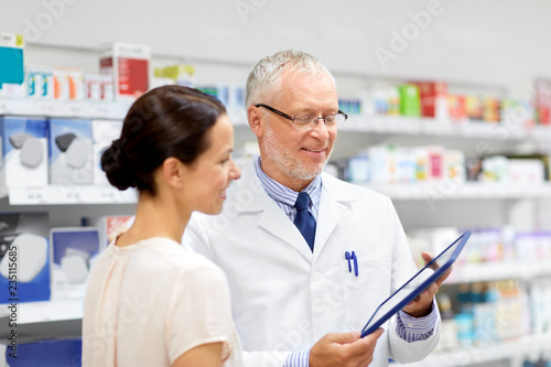 medicine  healthcare and technology concept - senior apothecary and female customer with tablet pc computer at pharmacy
