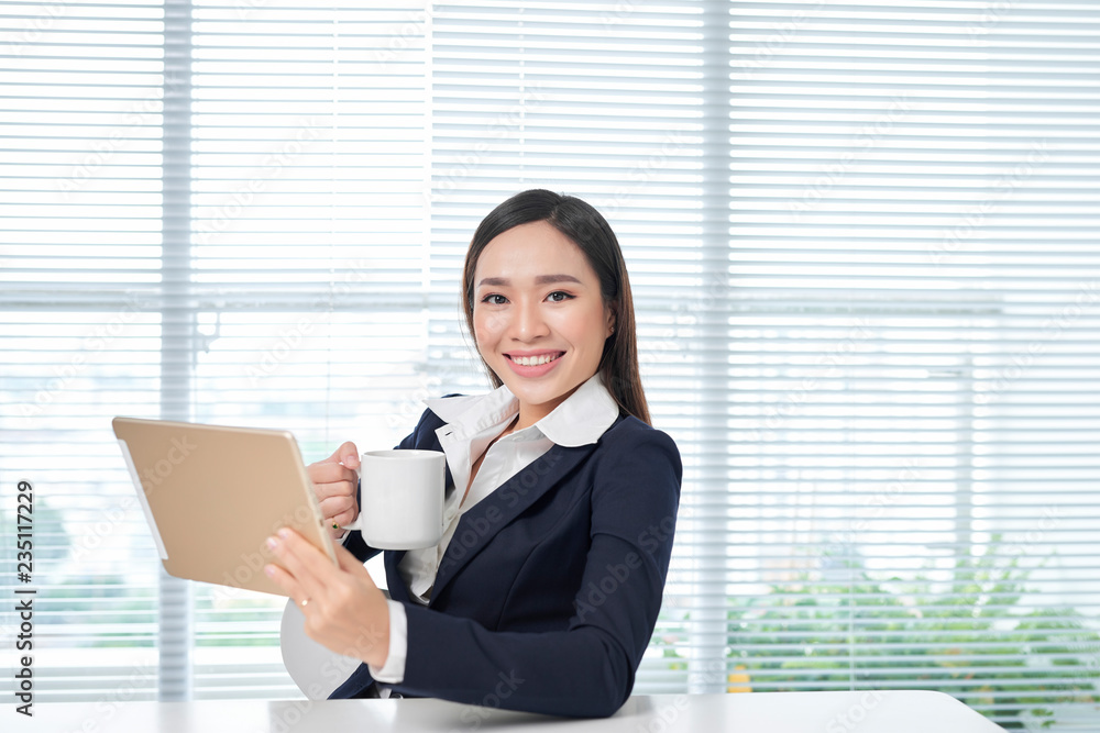 Smiling asian businesswoman sitting in bright office Smiling asian businesswoman sitting in bright office