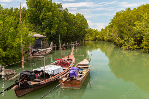 Traditional Thai Longtail fishing boats in shallow water in a sheltered mangrove forest