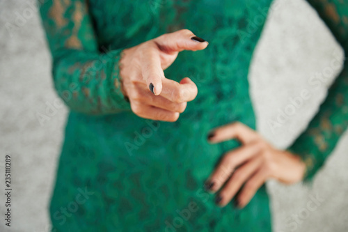 Close-up of slim young woman in evening dress pointing at you