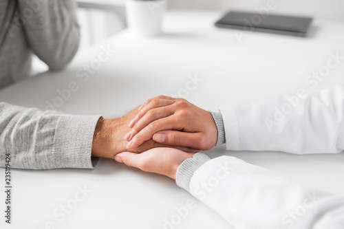 medicine  healthcare and old age concept - close up of young doctor holding senior patient hand