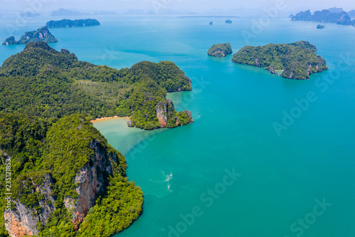 Aerial drone view of a beautiful, isolated tropical sandy beach surrounded by dense, mountainous jungle