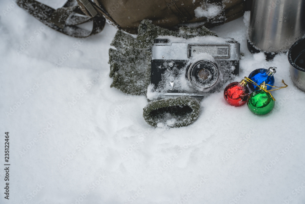 vintage camera in snow, the concept of Christmas holidays and gifts and sale, winter holidays and vacation, backpack, a thermos with coffee and a warm blanket, Christmas decorations