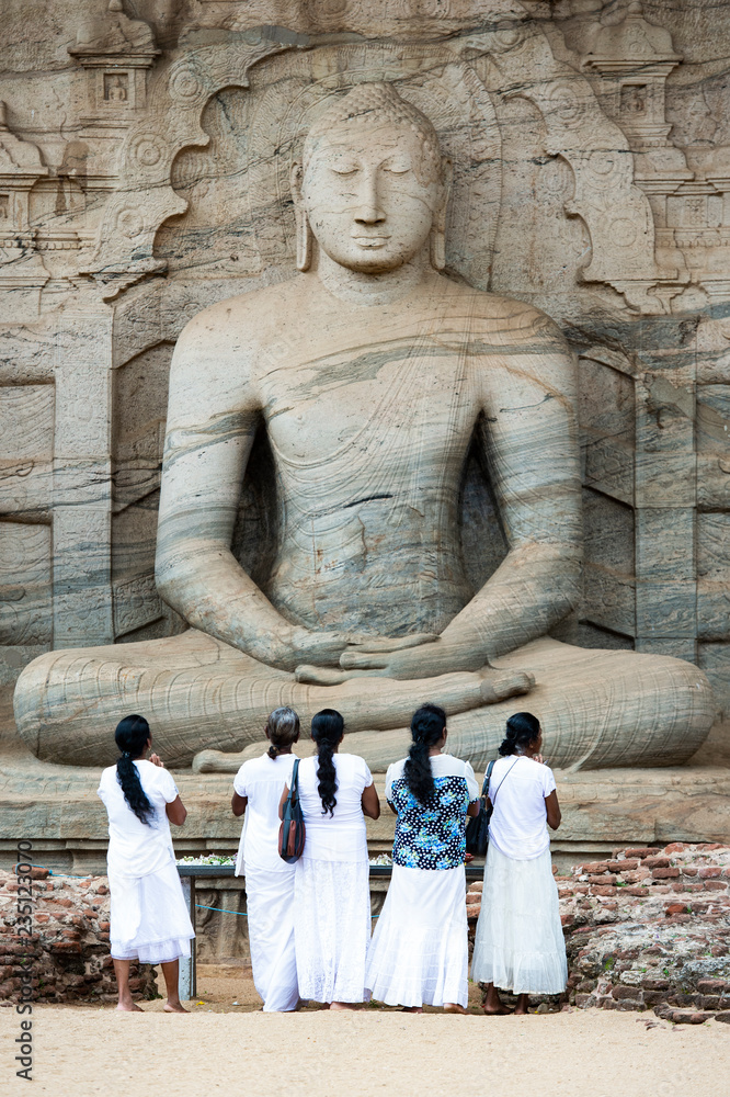 Five religious women are standing and admiring the great Samadhi Statue in Polonnaruwa, Sri Lanka.