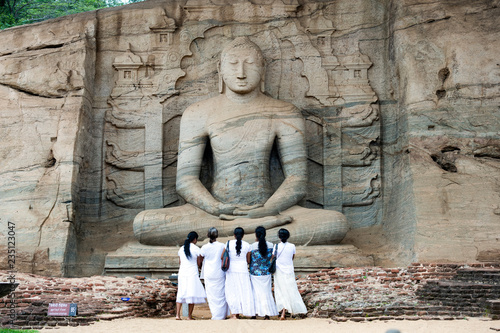 Five religious women are standing and admiring the great Samadhi Statue in Polonnaruwa, Sri Lanka. photo