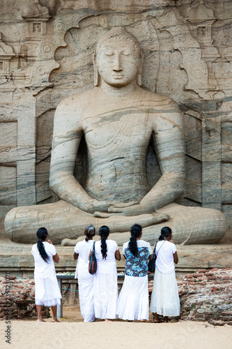 Obraz na płótnie Five religious women are standing and admiring the great Samadhi Statue in Polonnaruwa, Sri Lanka. w salonie