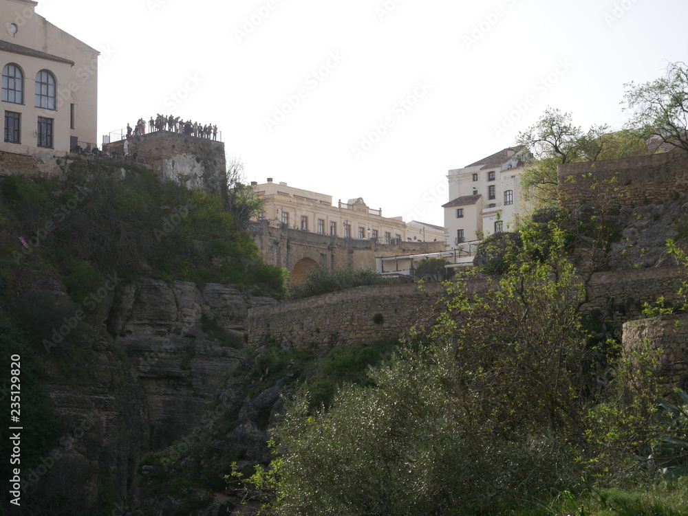 View of an old bridge over a canyon next to white buildings in Ronda, Spain
