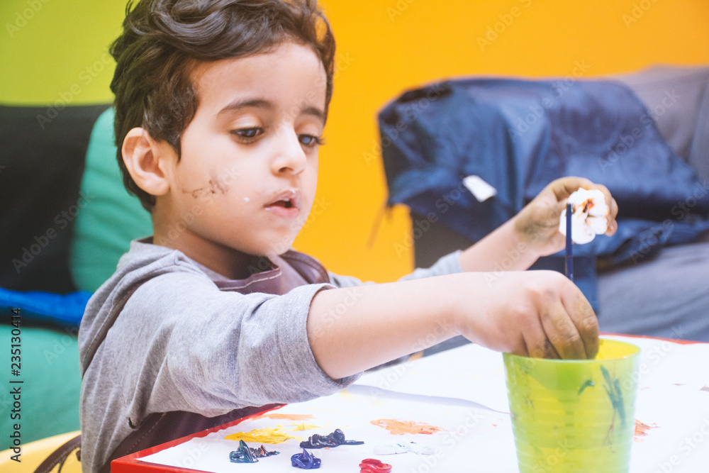 Obraz premium little boy painting sketchpad with a brush and water color paint, close up of his hands, child hoppy