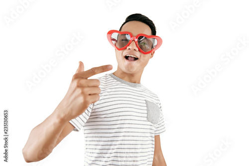 Portrait of young handsome Asian man wearing trendy heart-shaped sunglasses posing on camera against white background