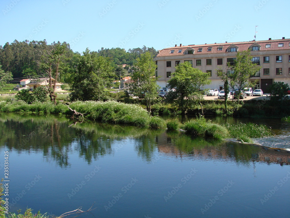 Panorama of residential buildings on the river bank, which are reflected on the water surface on a clear sunny spring day.