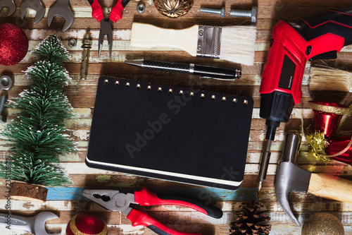 Merry christmas and Happy New year Craftsman Workspace background concept, Variety of handy DIY tools with Christmas ornament decoration. Top view with blank space notebook for your text.