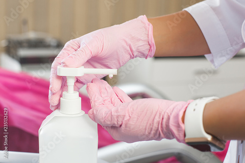 Woman`s hands wearing latex gloves close up still. sterilization gel in medical clinic. Cosmetologist processing her hands with professional disinfection agent photo