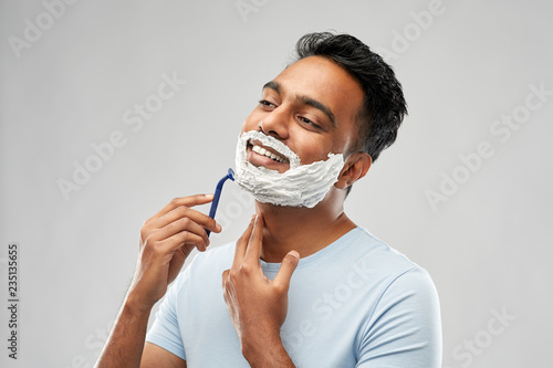 Εκτύπωση καμβά grooming and people concept - young indian man shaving beard with manual razor b