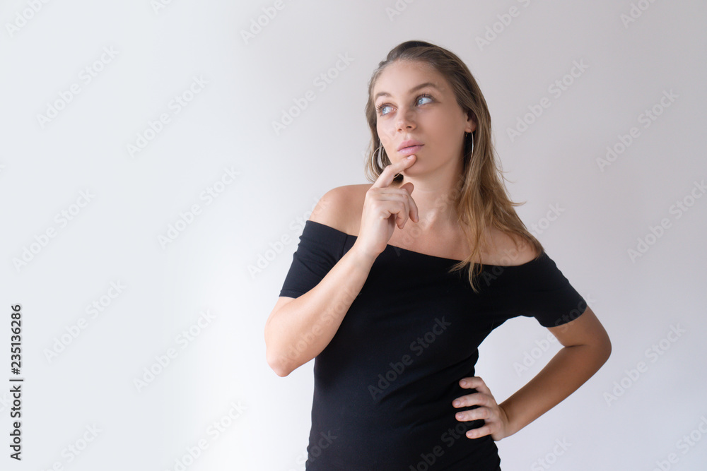 Pensive Caucasian girl touching chin and looking aside. Young beautiful female client choosing cosmetic products. Wellness solution concept Pensive Caucasian girl touching chin and looking aside. Young beautiful female client choosing cosmetic products. Wellness solution concept