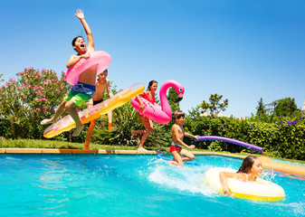 Happy friends jumping in pool on the vacations