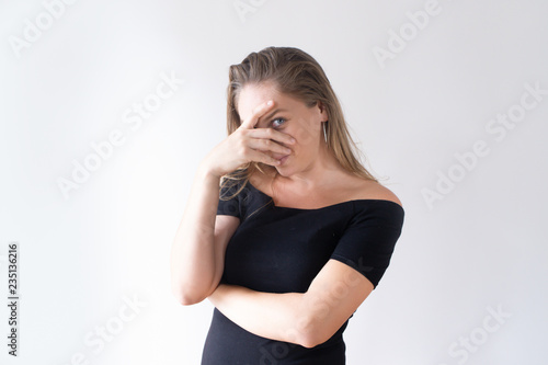 Intrigued pretty Caucasian girl covering face and looking at you. Portrait of young female manager having new idea. Inventive specialist concept