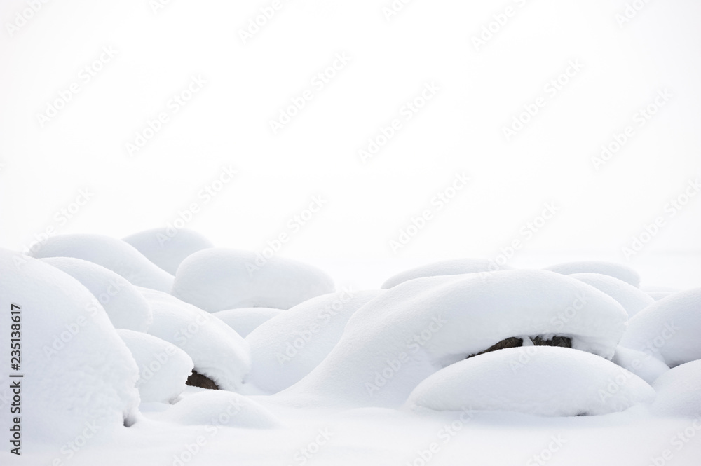 Soft newly fallen snow covering beach rocks.