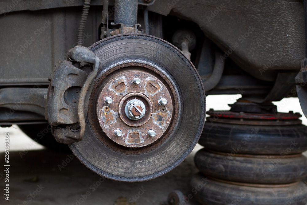 Inspection of the brake disc of an old wheel of a car raised on a jack. Worn brake disc to be replaced. The emergency state of the brake disc.