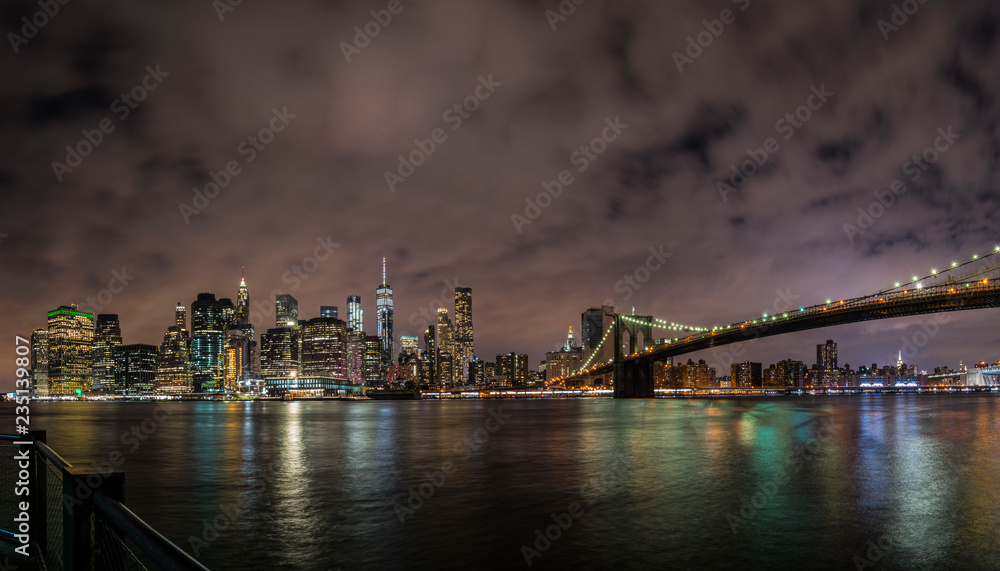 New York City Manhattan downtown panorama at night with skyscrapers illuminated over east river