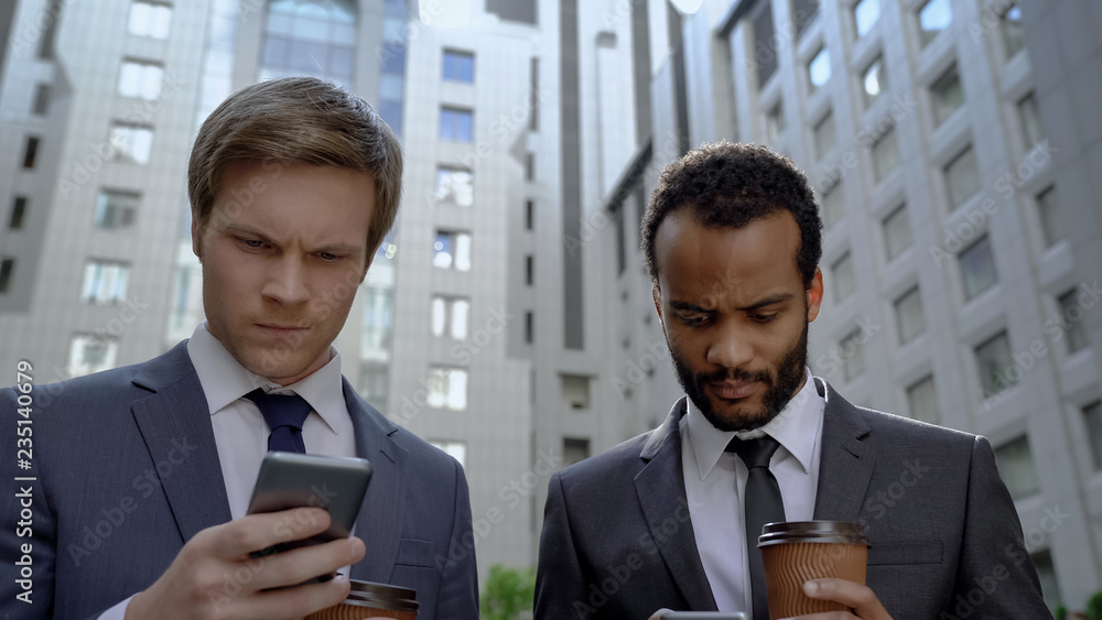Pensive businessmen checking stock market news using apps for phones, gadget Pensive businessmen checking stock market news using apps for phones, gadget
