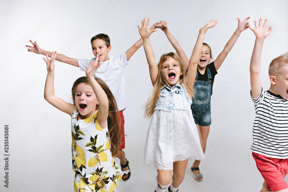 Obraz premium Group of fashion cute preschooler kids friends running together and looking at camera on a white studio background. The friendship, fashion, summer concept. Space for text.