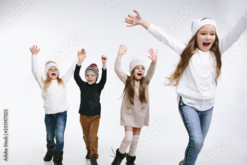 Group of kids in bright winter clothes, isolated on white studio. Fashion, childhood, happy emotions concept