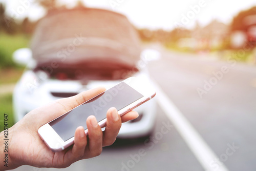 Fotografie close up female hand using a mobile smart phone call a car mechanic ask for help assistance because car broken on the roadside