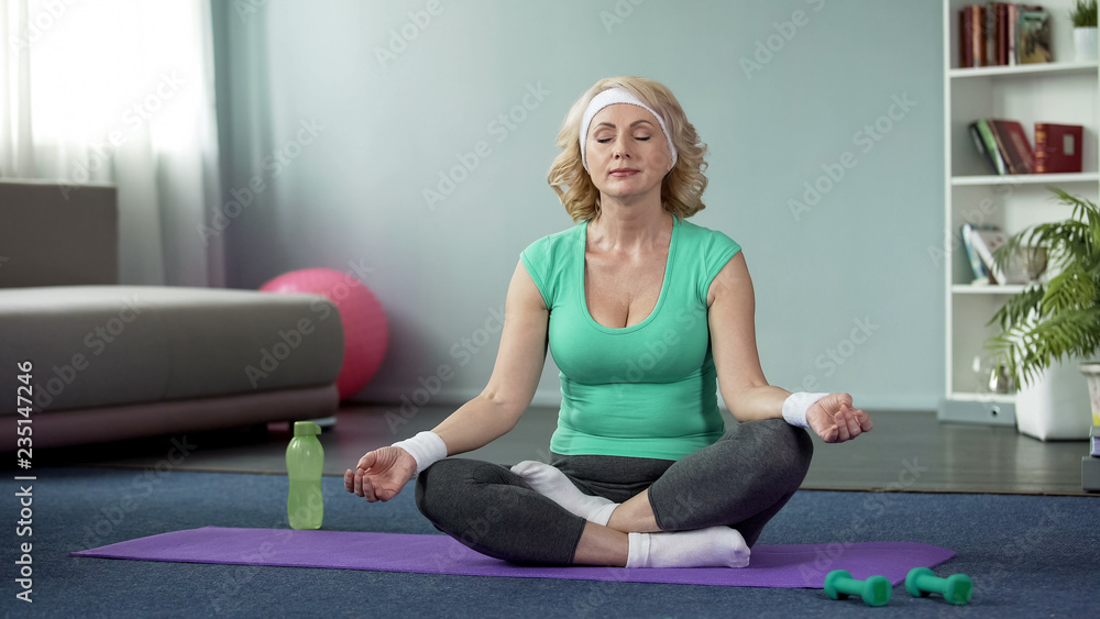 Pretty senior female meditating in lotus pose, active lifestyle, health care Pretty senior female meditating in lotus pose, active lifestyle, health care