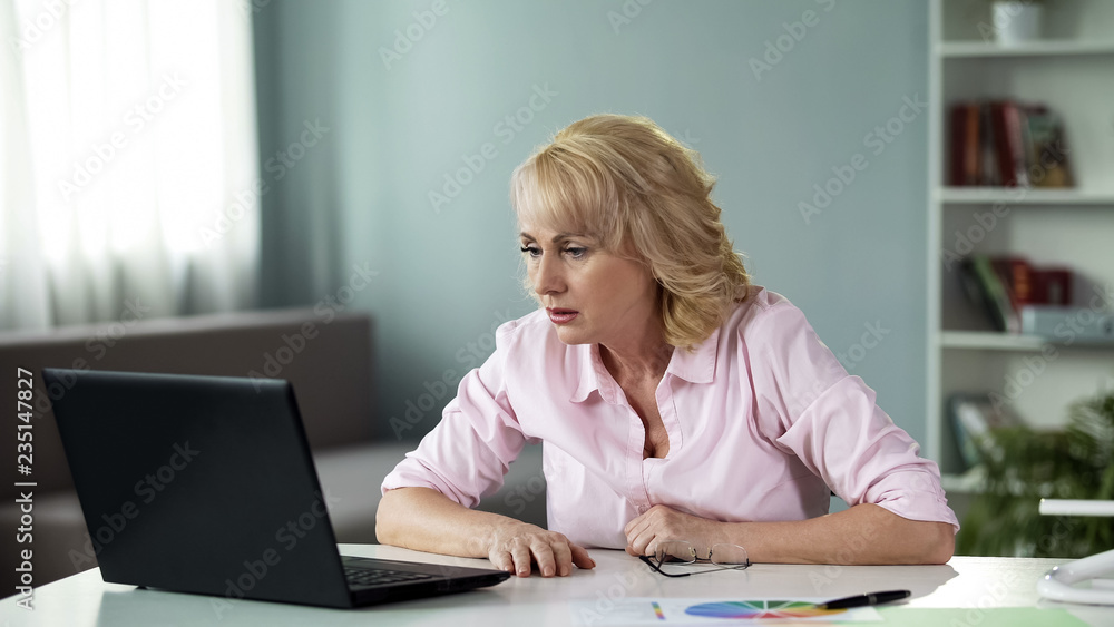 Surprised senior lady watching video online on laptop at home, reading news Surprised senior lady watching video online on laptop at home, reading news