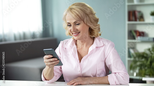 Fotografi Adult woman looking at pictures of her grown-up children with warmth and love