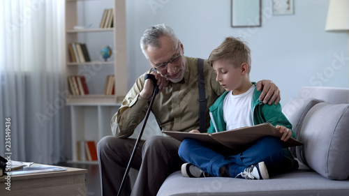Granddad reading book with boy, doing homework together, upbringing generation © motortion