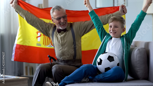 Grandpa waving Spanish flag, together with boy rejoices victory of football team