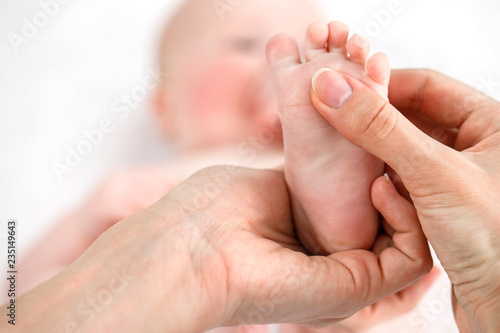 Mother does a foot massage to a newborn baby. mother's care. healthy lifestyle. Face is blurred in background. Close-up