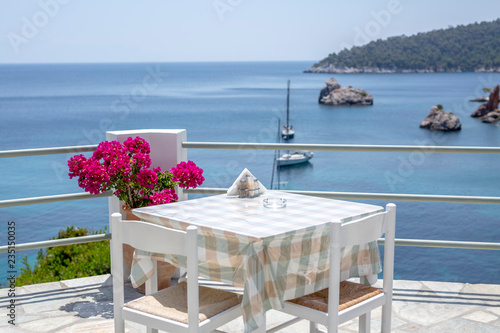 Restaurant tables waiting for customers by the sea outdoor terrace in Skopelos, Greece.