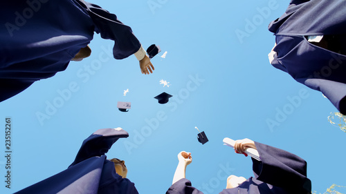 University graduates tossing up their square caps student tradition, bottom view