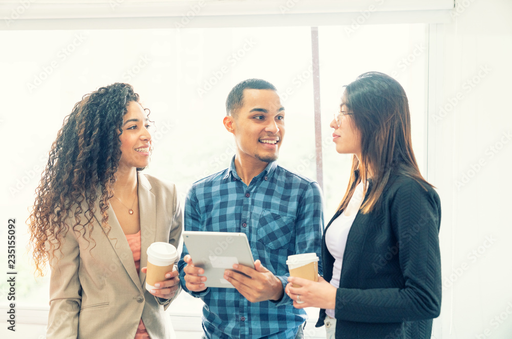 Happy multiethnic coworkers discussing results in front of a tablet and coffee cups.