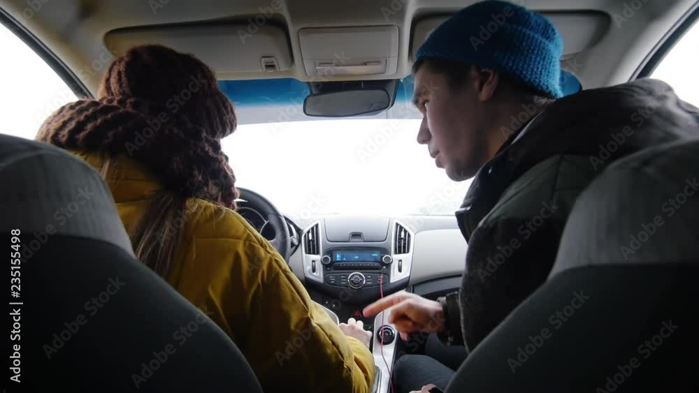 A young man showing a young woman the steps how to start the car. Winter A young man showing a young woman the steps how to start the car. Winter