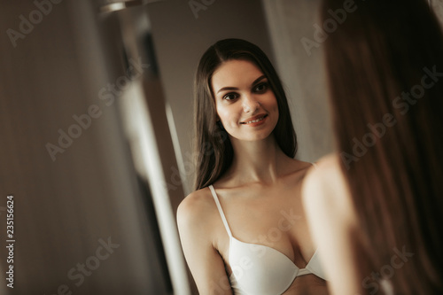 Portrait of beaming woman examining her reflection. She wearing white bra indoor Free Download Portrait of beaming woman examining her reflection. She wearing white bra indoor - GFXLoad