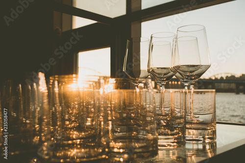 empty glasses of whiskey and wine at sunset on indoor table with river view windows