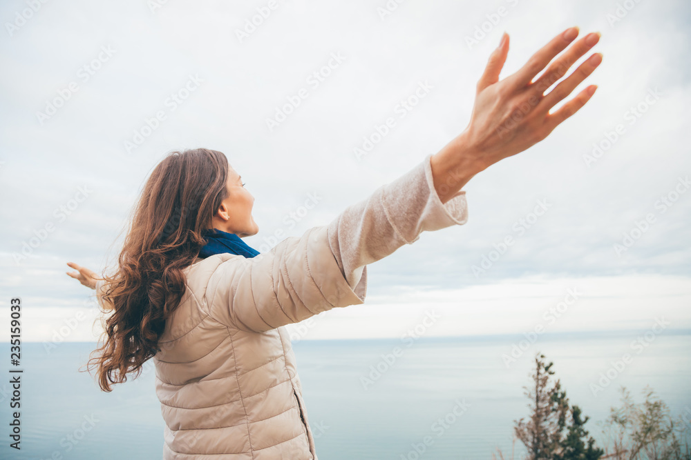 Young woman is enjoying nature with panoramic sea view from a cliff. Concept of female freedom and love for life Young woman is enjoying nature with panoramic sea view from a cliff. Concept of female freedom and love for life