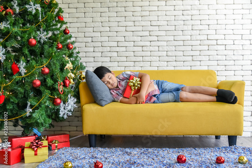 An Asian boy sleep on a yellow sofa, And hug the gift box He received it on Christmas Day, to holiday and New Year concept. photo