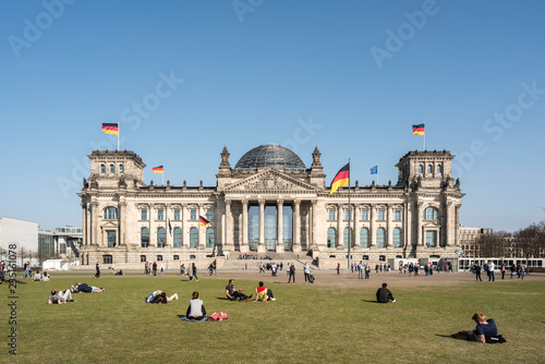 The facade of Reichstag building in Berlin, many unidentified visitors and tourists in foreground.