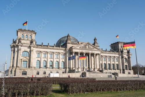 The facade of Reichstag building in Berlin, many unidentified visitors and tourists in foreground.