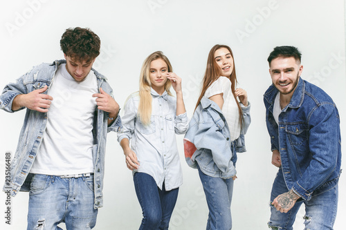 Group of smiling friends in fashionable jeans. The young men and woman posing at studio. The fashion, people, happy, lifestyle, clothes concept