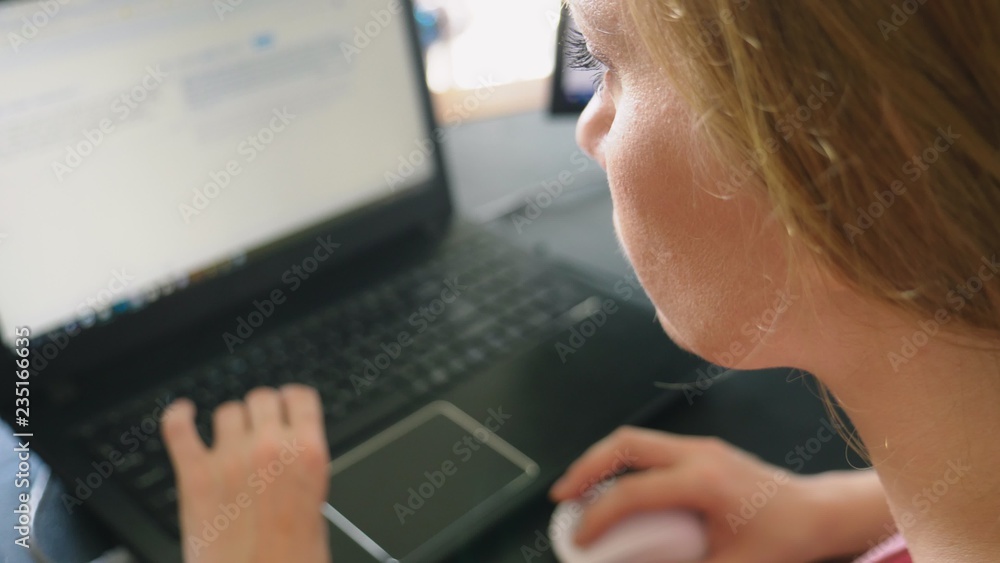 woman working on a laptop while sitting at a desk. woman working on a laptop while sitting at a desk.