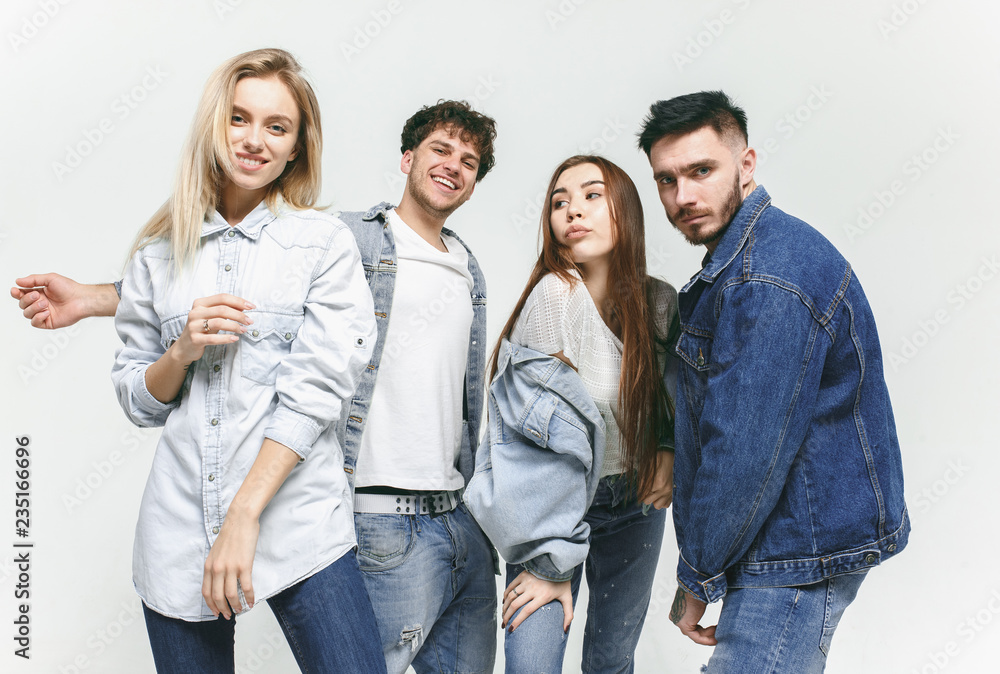 Group of smiling friends in fashionable jeans. The young men and woman posing at studio. The fashion, people, happy, lifestyle, clothes concept Group of smiling friends in fashionable jeans. The young men and woman posing at studio. The fashion, people, happy, lifestyle, clothes concept