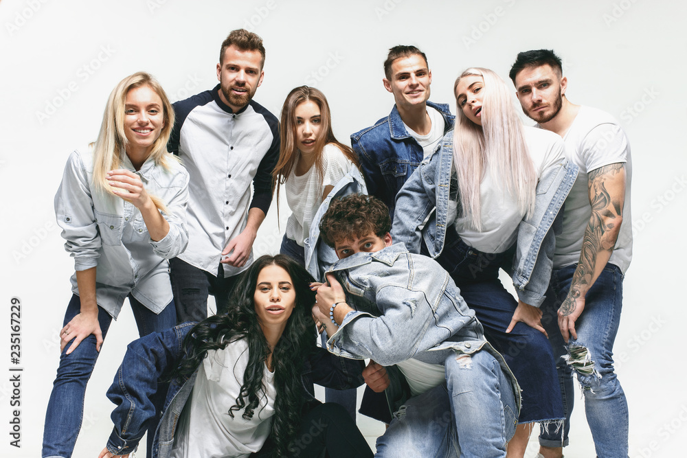 Group of smiling friends in fashionable jeans. The young men and woman posing at studio. The fashion, people, happy, lifestyle, clothes concept Group of smiling friends in fashionable jeans. The young men and woman posing at studio. The fashion, people, happy, lifestyle, clothes concept