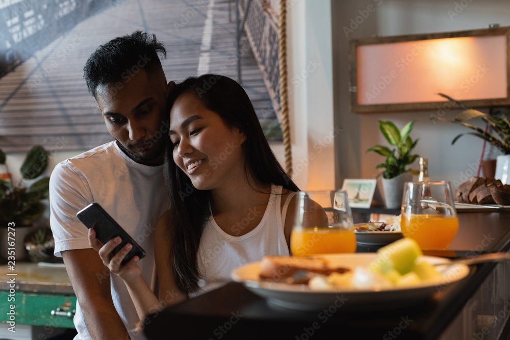 Couple using mobile phone in kitchen Couple using mobile phone in kitchen